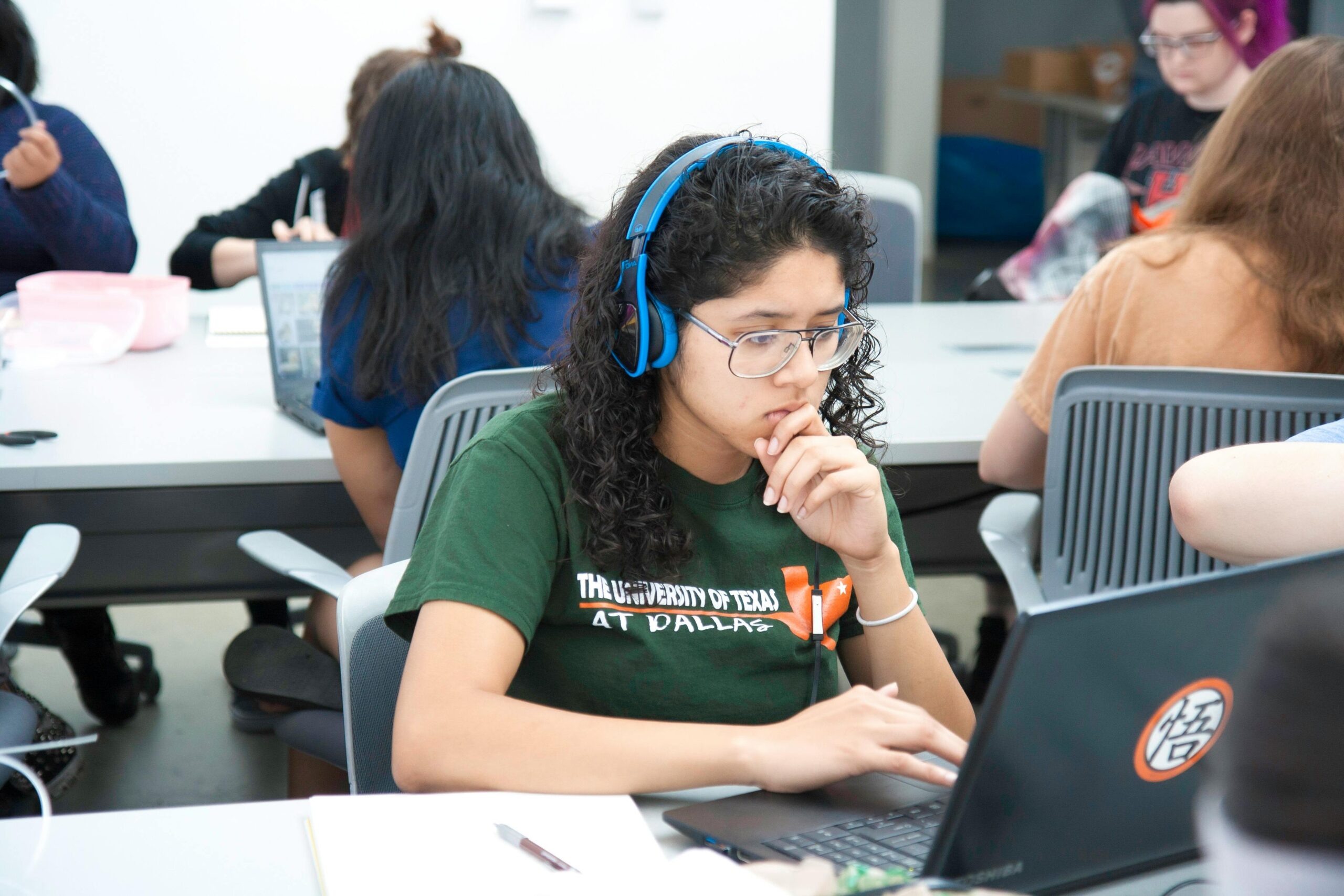 College student with headphones studying at a university using a laptop.